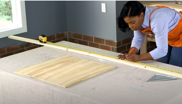 Woman measuring a board with a tape measure.