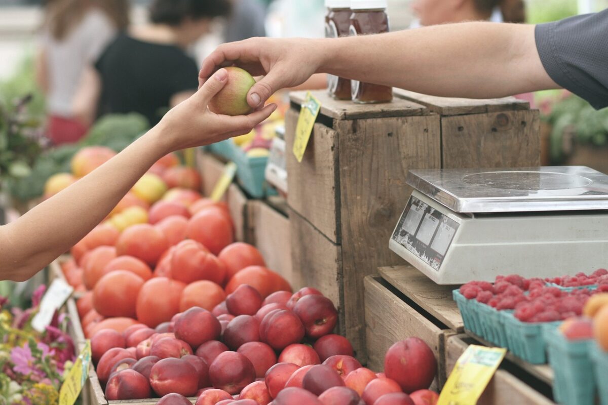 guy giving girl an apple at a farmers market