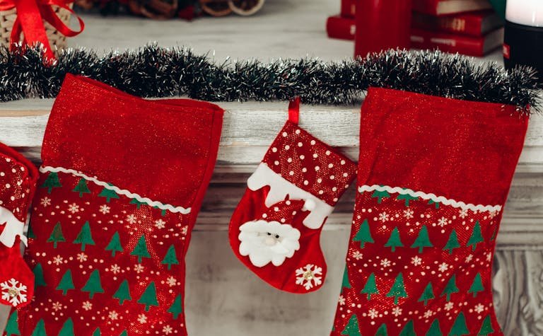 Colorful Christmas stockings hanging on a decorated mantlepiece.